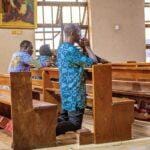 Adults kneeling and praying in a church in Benin City, Nigeria, depicting spirituality and devotion.