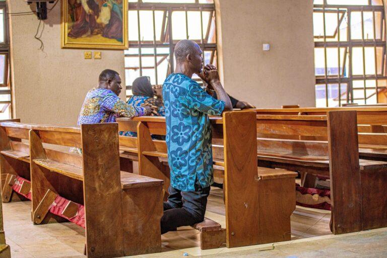 Adults kneeling and praying in a church in Benin City, Nigeria, depicting spirituality and devotion.