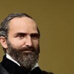 G.D. Watson, a man with a beard and receding hairline, in a suit.
