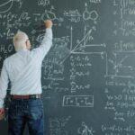 A professor writing complex formulas on a blackboard