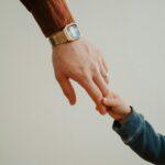 a person holding the hand of a child